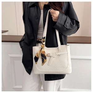 Detail of white crocodile pattern tote bag with decorative silk scarf and buckle