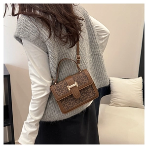 Detail of a brown leather crossbody bag with vintage GK pattern and gold buckle