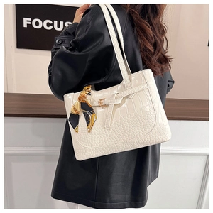 Detail view of white crocodile pattern tote bag with floral scarf handle decoration