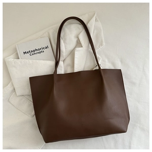 Detailed top view of a vintage dark brown leather tote bag on a white striped blazer