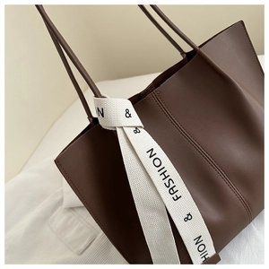 Close-up of deep brown tote bag with matte PU leather and fashion ribbon detail