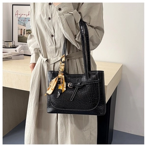 Detail of black crocodile texture tote bag with a decorative silk scarf on the handle