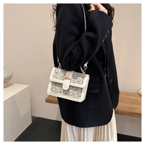 Detail of contrast stitching and metallic buckle on small crossbody bag with GK pattern