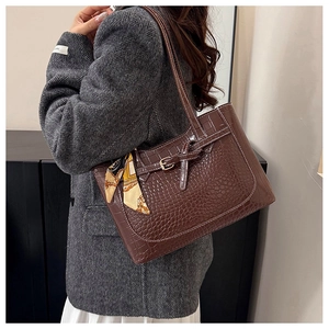Detail of dark brown faux crocodile leather tote bag with silk scarf on handle