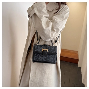 Detail of a chic shoulder bag featuring GK monogram print and a gold H-shaped clasp