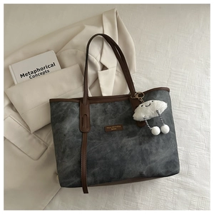 Macro detail of dark grey tote with brown leather trim and plush cloud charm