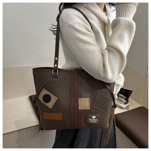 Detail of dark brown tote bag with vintage patches and fashion lucky heart emblem