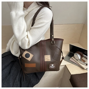 Detail of vintage brown tote bag featuring retro patches and vertical stripes on side