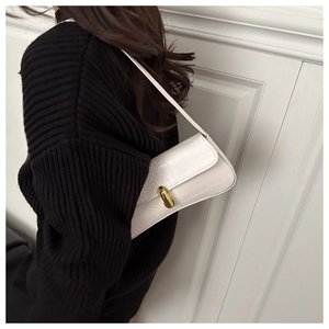 Détail d'un sac baguette blanc à motif crocodile avec fermoir capsule en métal doré
