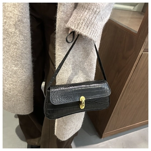 Detail shot of black crocodile embossed faux leather bag with elegant gold rotary lock