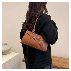 Detail of vintage brown rectangular underarm bag with silver metal buckle on a model