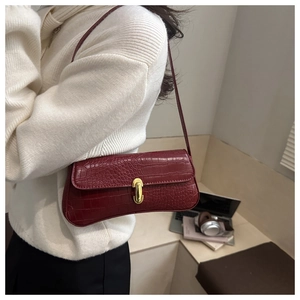 Détail d'un sac sous les aisselles bordeaux à motif crocodile et fermoir doré