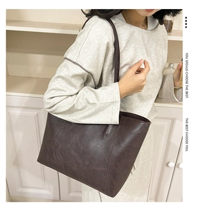 Detail view of large dark brown tote bag with premium leather texture and vertical stitching