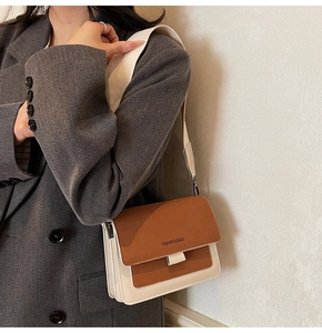 Detail of two-tone brown and beige crossbody bag with a wide strap on a model