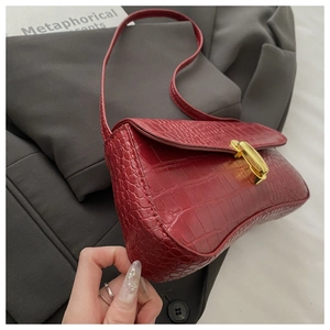 Gros plan du sac bandoulière bordeaux motif crocodile avec un fermoir doré élégant