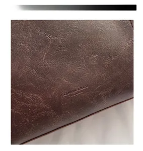 Detail of soft brown pebble leather texture with embossed fashion text on a tote bag