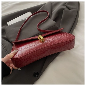 Détail du cuir gaufré crocodile bordeaux et fermoir doré sur le sac à bandoulière