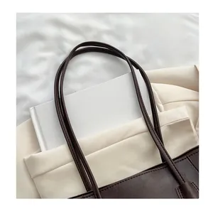 Detail of dark brown leather tote bag showing slim dual handles and fine grain texture