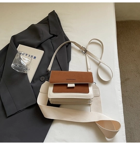 Detail of minimalist crossbody square bag featuring dual straps and contrasting textures