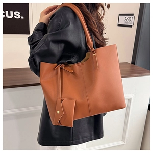 Detailed side view of brown tote bag with a matching mini pouch and leather texture