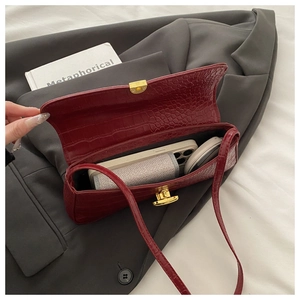 Detail of burgundy crocodile pattern handbag showing interior capacity for phone and makeup