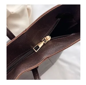 Detail of premium gold metal zipper and smooth dark brown leather texture on tote bag