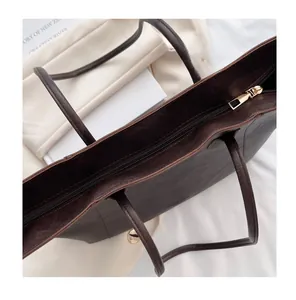 Detail of smooth gold metal zipper and premium dark brown leather texture on a tote bag