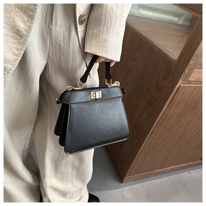 Détail d'un sac à main noir en cuir avec fermoir tournant doré et finitions métalliques