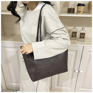 Detail view of large dark brown retro tote bag with textured leather and long straps