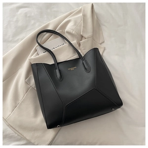 Close-up of black leather tote bag with gold lettering and silver protective feet