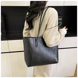 Rear view of model holding a black large-capacity tote bag with fine leather texture