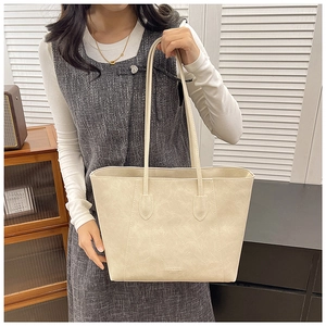 Detail view of the cream tote bag with thin dual straps and vintage leather texture