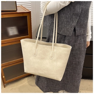 Detail of a minimalist cream leather tote bag shown with an elegant vintage outfit