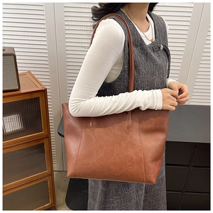 Retro brown leather tote bag with long handles shown in a stylish minimalist setting
