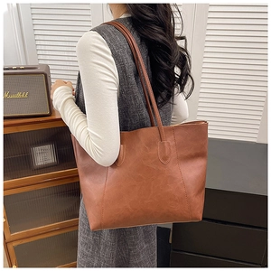Detail of a brown PU leather tote bag with wide stitching and comfortable long straps