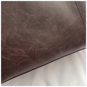 Close-up of retro brown oil-wax leather texture with neat stitching and embossed logo