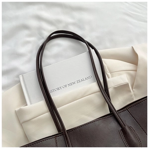 Detailed close-up of dark brown leather tote bag with long handles for daily commute