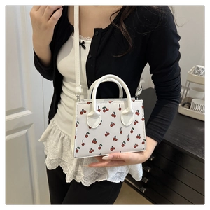 Détail du sac à main blanc avec motif cerise rouge, doubles poignées et bandoulière
