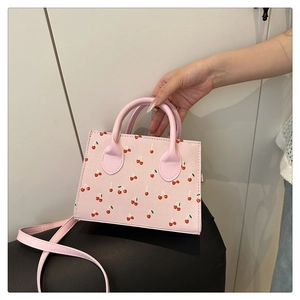 Détail du sac à main rose à motif cerises avec doubles poignées cylindriques