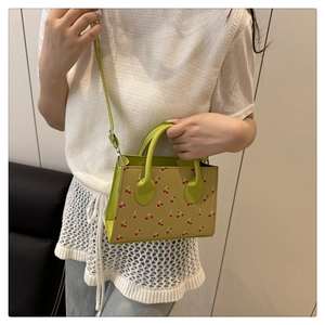 Détail du mini sac cabas tendance avec imprimé cerise et bandoulière verte réglable