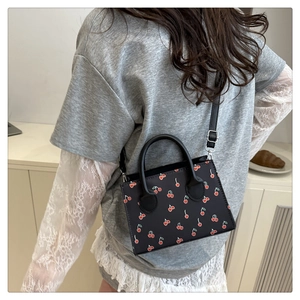 Close-up of black cherry print crossbody bag showing the elegant top handle and strap