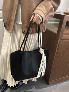 Classic black tote bag with vertical stitching and decorative fashion letter ribbon