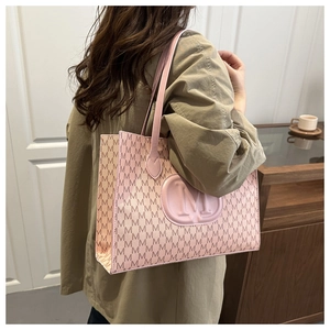 Close-up of pink tote bag featuring embossed M logo and monogram pattern on premium leather