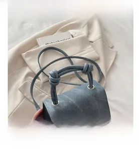 Detail of blue denim shoulder bag with unique knotted handle and gold ring hardware