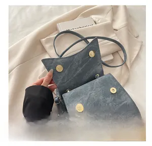 Detail of four golden magnetic clasps and denim texture on an elegant blue shoulder bag