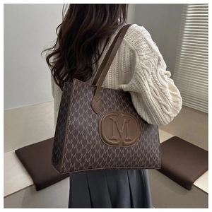 Detail showing the embossed M logo and monogram pattern on this brown tote bag