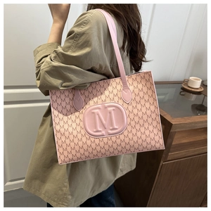 Detail of pink tote bag featuring M monogram pattern and embossed circular logo