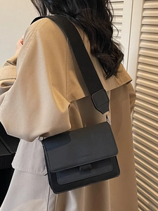 Minimalist matte black crossbody bag with wide shoulder strap and sleek rectangular flap design