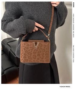 Detail of leopard print handbag with golden V-shaped buckle and versatile shoulder strap