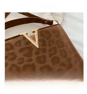 Detailed macro view of the gold V logo hardware on a leopard print tote handbag